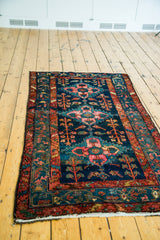 Vintage Hamadan rug detail: dark blue field, gem-tone geometric medallions, rust border.
