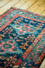 Vintage Hamadan rug's deep indigo field, rust border, and colorful geometric plant motifs.