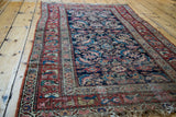 Antique Northwest Persian rug corner, distressed fringe, faded red and blue herati patterns.