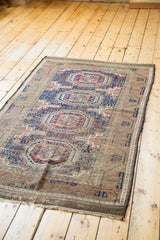 Secured edge of antique Belouch rug displaying navy and chestnut geometric tribal pattern.