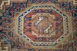 Interlocking geometric tribal motifs in deep chestnut, navy, and tobacco on an antique Belouch rug.