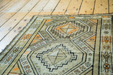 Close-up of vintage Caucasian rug, geometric tribal designs in ivory, charcoal, and orange.
