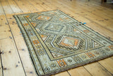 Geometric tribal patterns in ivory, charcoal, and orange highlighting a Vintage Caucasian rug edge.