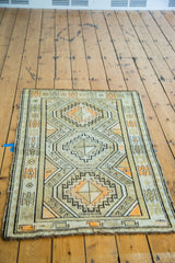 Charcoal, orange, ivory geometric tribal pattern on vintage Caucasian rug corner, secured end.