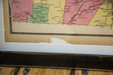 Torn, browned paper edge of an antique Bedford, NY map in its black frame.