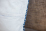 Indigo pillow side with vertical blue and white stripes and thin blue dashed stitch.
