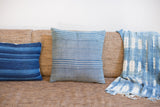 Detail of handmade indigo blue throw pillow with thin white stripes.