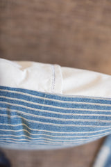 Double-stitched white canvas back of an indigo striped throw pillow.