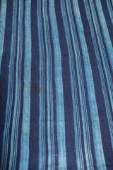 Collectible hand woven indigo blue textile with varying stripes and unique patina.