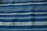 Hand-woven cotton indigo throw, featuring varied blue stripes and authentic textile texture.
