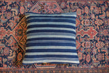 Finely handwoven indigo throw pillow with varied dark and light blue stripes.