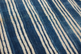 Close-up of a vintage indigo textile, featuring hand-dyed blue stripes and visible weave.