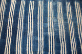 Textured vintage indigo textile with varied blue and off-white vertical stripes.