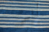 Detail of hand-woven African indigo textile, featuring varied blue and off-white stripes.