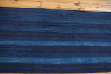 Hand woven indigo textile runner, showing varied blue stripes and natural textured finish.