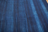 Vintage hand woven African indigo textile with varied blue stripes and cotton texture.