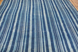 Angled close-up of a collectible handwoven indigo blue striped cotton textile.