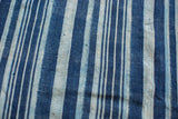 Textural detail of vintage hand-woven indigo cotton with varying blue stripes.