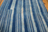 Detailed view of hand-woven indigo cotton textile, highlighting varied blue stripes and subtle texture.