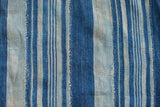 Indigo blue striped textile with varied vertical bands and nuanced hand-woven texture.