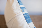 Close-up of light indigo striped pillow side with ivory canvas and dark stitch.