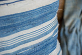 Textured close-up of light indigo striped pillow textile, highlighting visible mending.