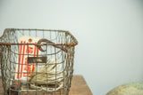 Industrial wire basket with irregular spacing, rusted patina, and original metal number tag.