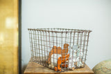 Aged silvery Fred Medart wire basket with number tag, holding small wooden toys.