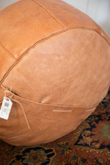Camel brown Moroccan leather pouf with distressed texture and bottom lacing.