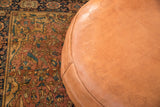 Camel brown leather pouf, flower fan stenciling, and lightly distressed texture.