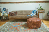 Natural brown leather Moroccan pouf ottoman, low-slung, with subtle stenciled patterns.