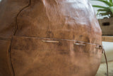 Natural brown leather pouf with lacing detail and antique-revival texture.