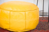 Lightly distressed fly yellow leather pouf, impressed fleur de lis and flower fan motifs.