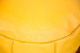 Fly yellow leather pouf showing raised flower fan pattern.