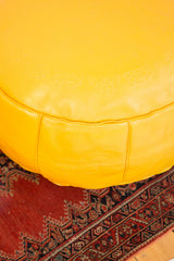 Fly yellow leather pouf side with embossed flower fan and fleur de lis motifs.