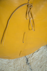 Handcrafted lacing detail on the thick mustard yellow leather of the Moroccan pouf.