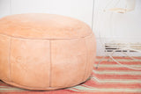 Embossed floral fan and fleur de lis patterns on nude leather pouf.