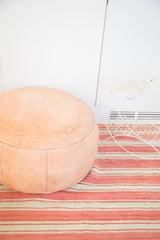Nude Moroccan leather pouf ottoman with subtle fleur-de-lis and floral stenciling.