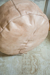 Nude leather pouf featuring visible hand-lacing detail and natural distressed texture.