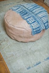 Nude leather pouf side with fleur de lis and flower stenciling, showing distressed texture.
