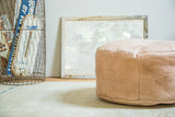 Distressed nude leather pouf with embossed fleur-de-lis and flower fan stenciling.