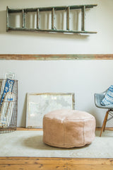 Nude leather Moroccan pouf with subtle floral stenciling and light distressing.