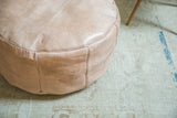 Embossed flower fan and fleur de lis motifs on a nude leather Moroccan pouf.