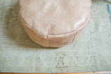 Nude Moroccan leather pouf featuring embossed flower fan patterns.
