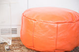 Tangerine orange leather pouf with embossed flower fan stenciling and distressing.