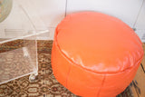 Tangerine orange leather pouf with subtle texture and flower fan stenciling.