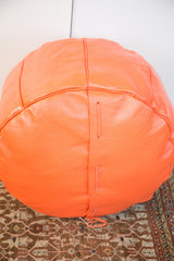 Tangerine orange leather pouf featuring side lacing and distressed texture.