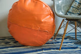 Hand-crafted lacing and lightly distressed tangerine orange leather on the pouf.