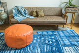 Antique Revival tangerine orange leather Moroccan pouf ottoman with floral stenciling.