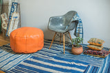 Tangerine orange leather pouf with fleur de lis and flower fan stenciling.